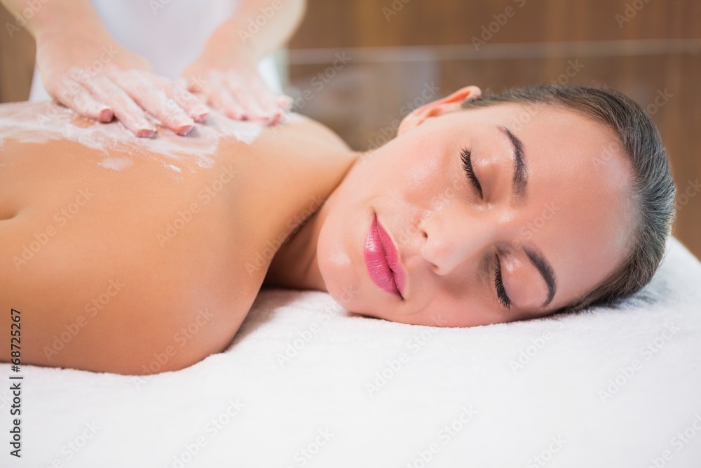 Attractive woman receiving back mask cream at spa center