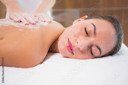 Attractive woman receiving back mask cream at spa center