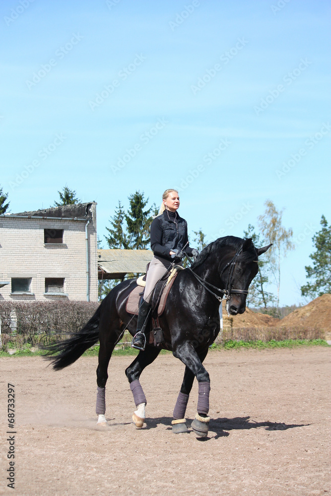 Blonde woman riding black horse Blonde woman riding black horse