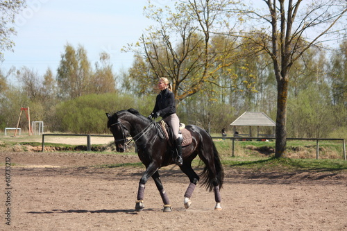 Blonde woman riding black horse