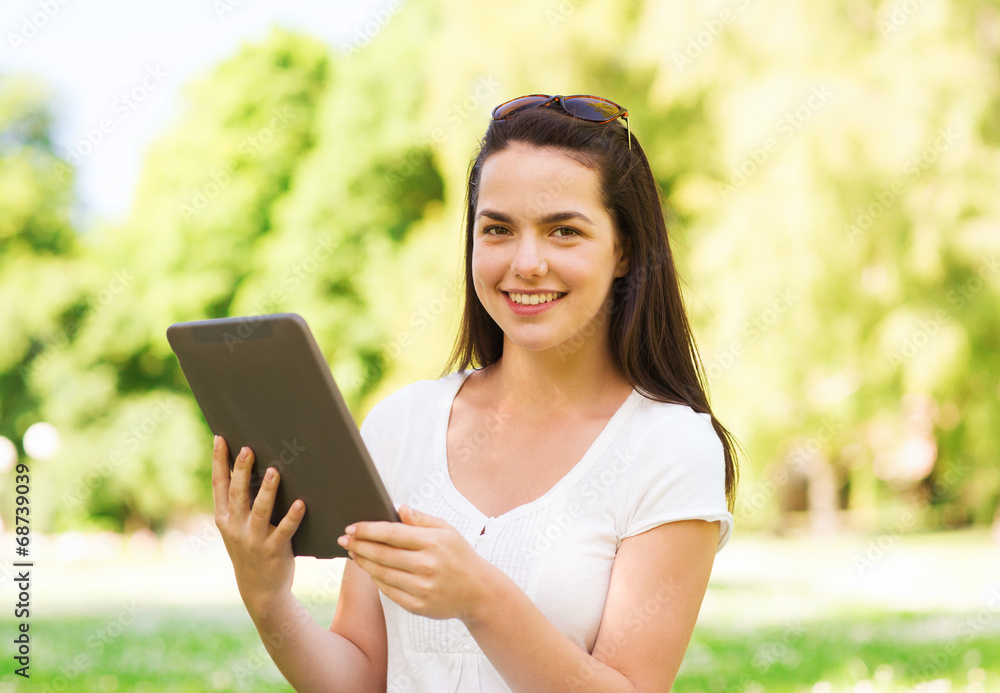 smiling young girl with tablet pc sitting on grass smiling young girl with tablet pc sitting on grass