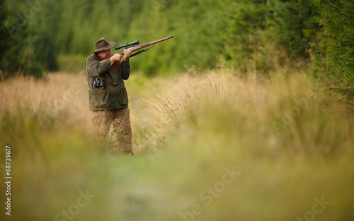 hunter with his rifle in spring forest, hunter holding a rifle