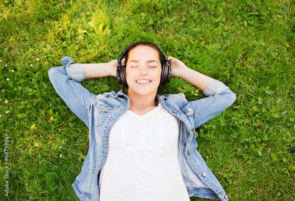 smiling young girl in headphones lying on grass smiling young girl in headphones lying on grass
