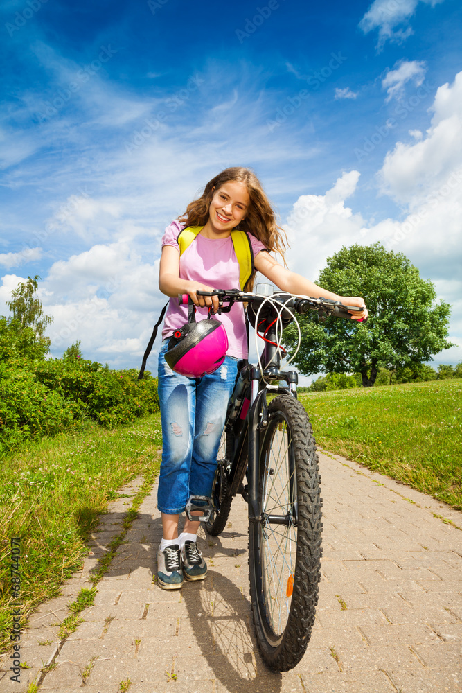 Girl with long hair holds her bike and helmet Girl with long hair holds her bike and helmet