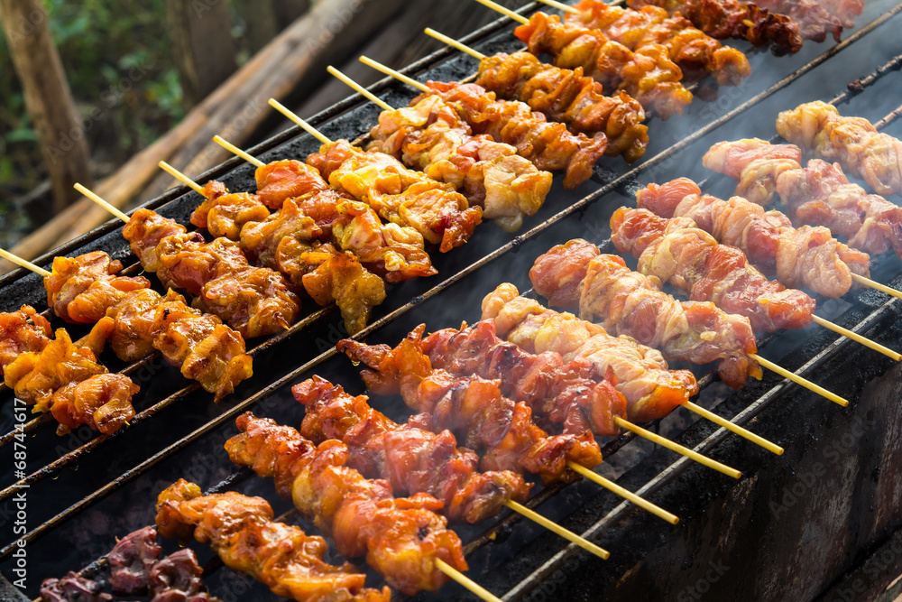 Skewer chicken pieces in a roasting on the grill and smoke