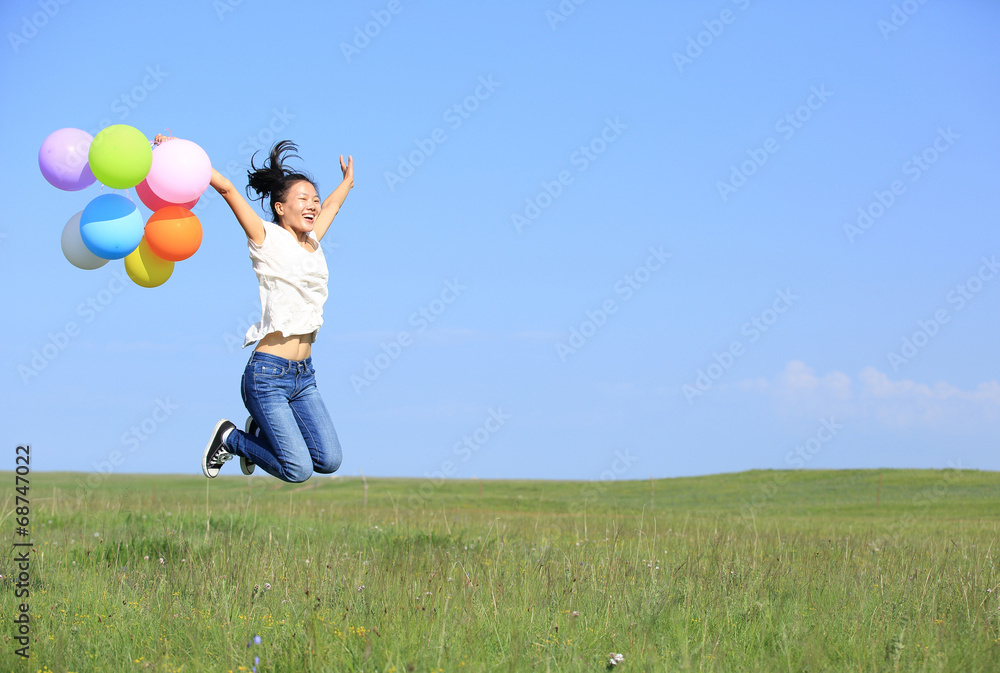Fototapeta premium young asian woman on green grassland with colored balloons 