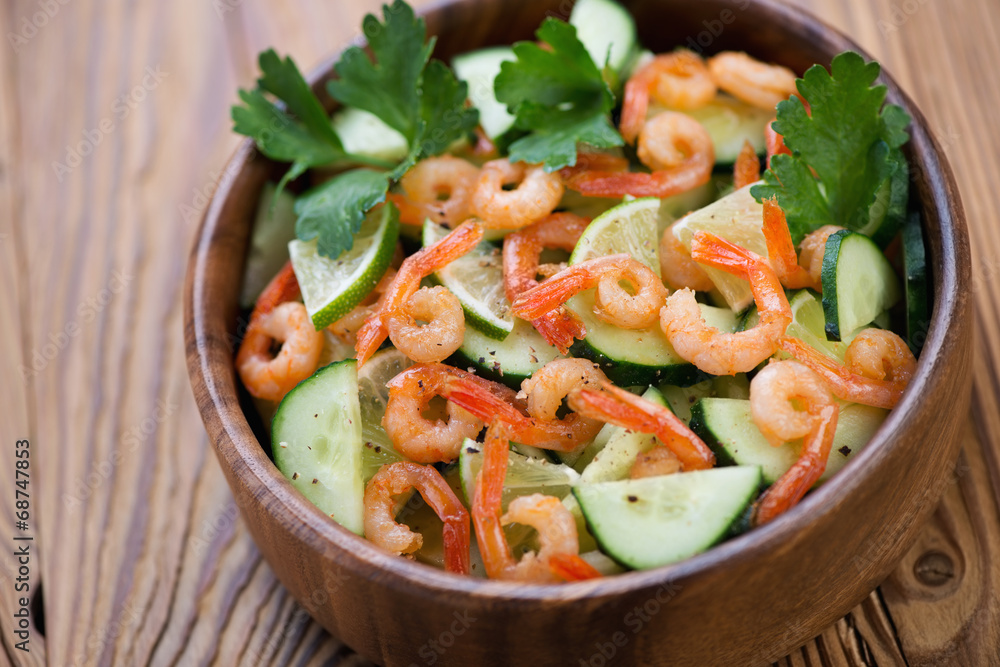 Salad with shrimps, cucumbers and lime in a wooden bowl Salad with shrimps, cucumbers and lime in a wooden bowl