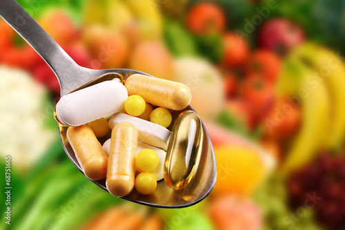 spoon with dietary supplements on fruits background photo