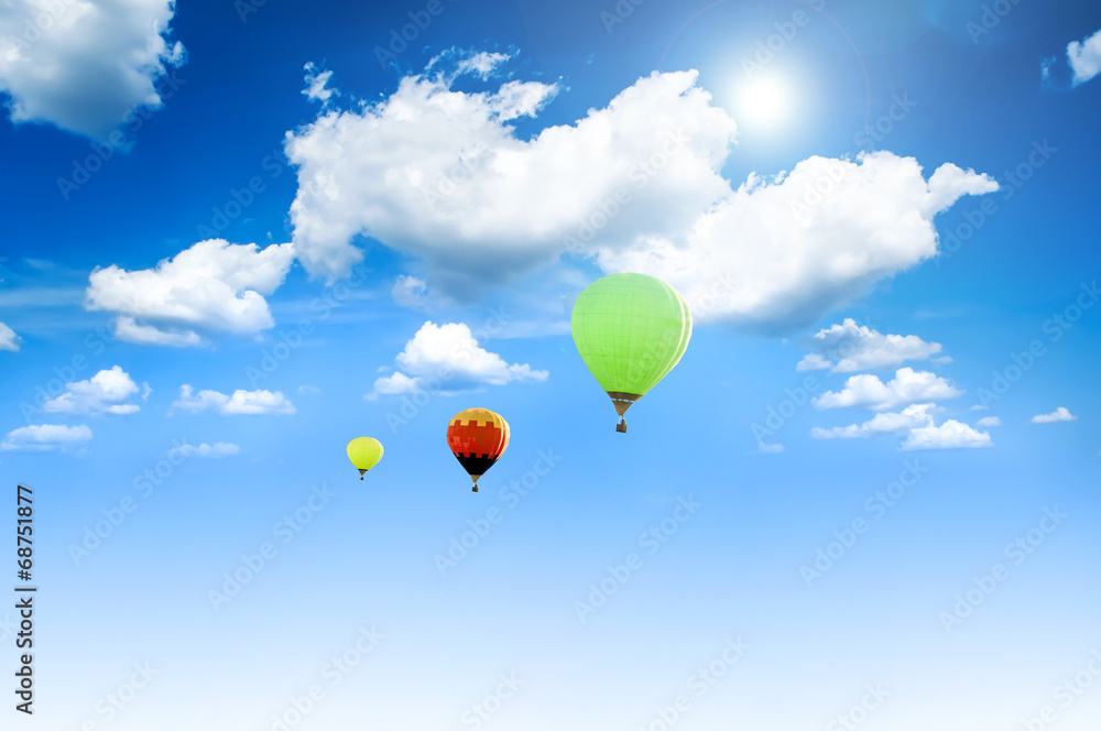 Fototapeta premium Balloons sunlit against a blue sky and clouds.