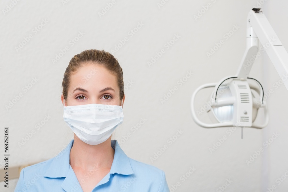 Dental assistant in mask looking at camera Dental assistant in mask looking at camera