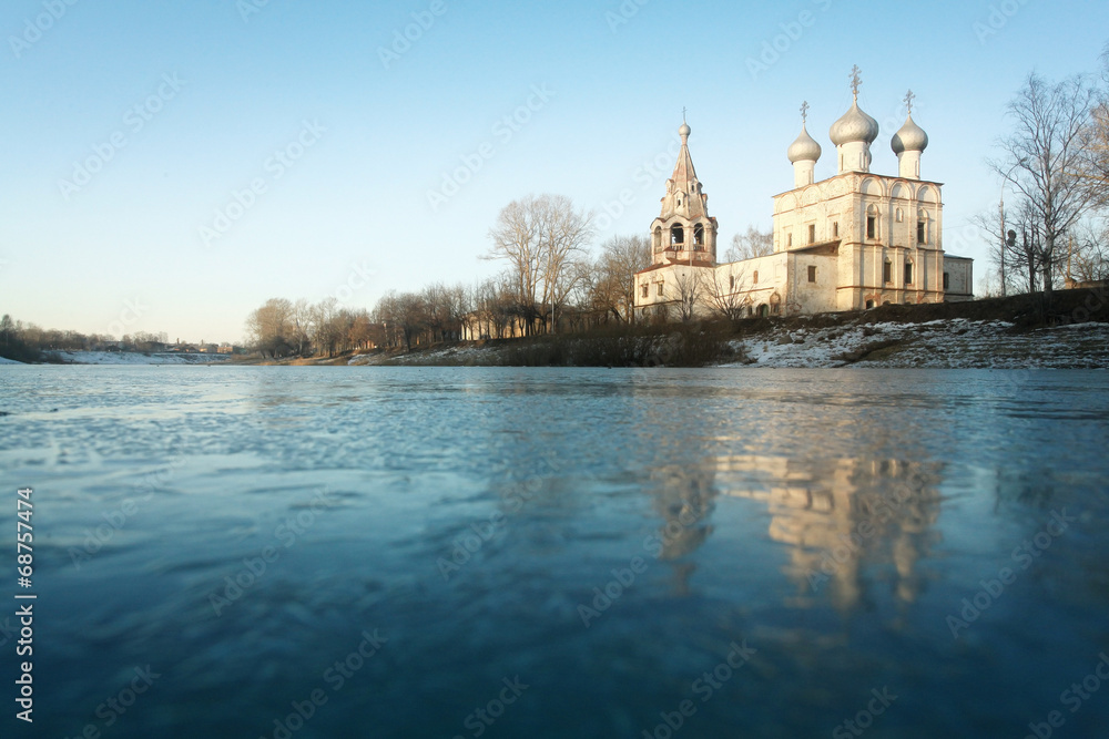 Fototapeta premium Church on the banks of the frozen river ice winter