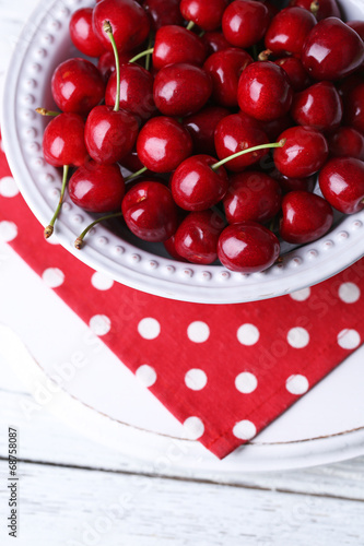 Sweet cherries on plate on wooden background