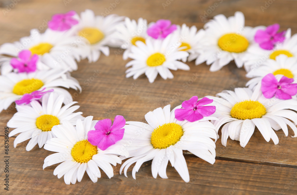 Obraz premium Chamomile wreath on brown wooden background