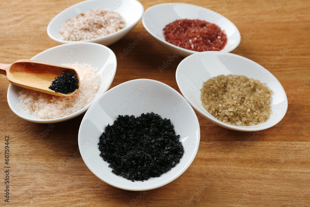 Variety of different sea salt in bowls on wooden table, close Variety of different sea salt in bowls on wooden table, close