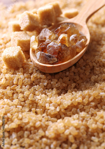 Reed sugar in wooden spoon on brown crystal sugar background photo