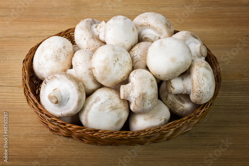 Fresh mushrooms in a basket on a wooden table