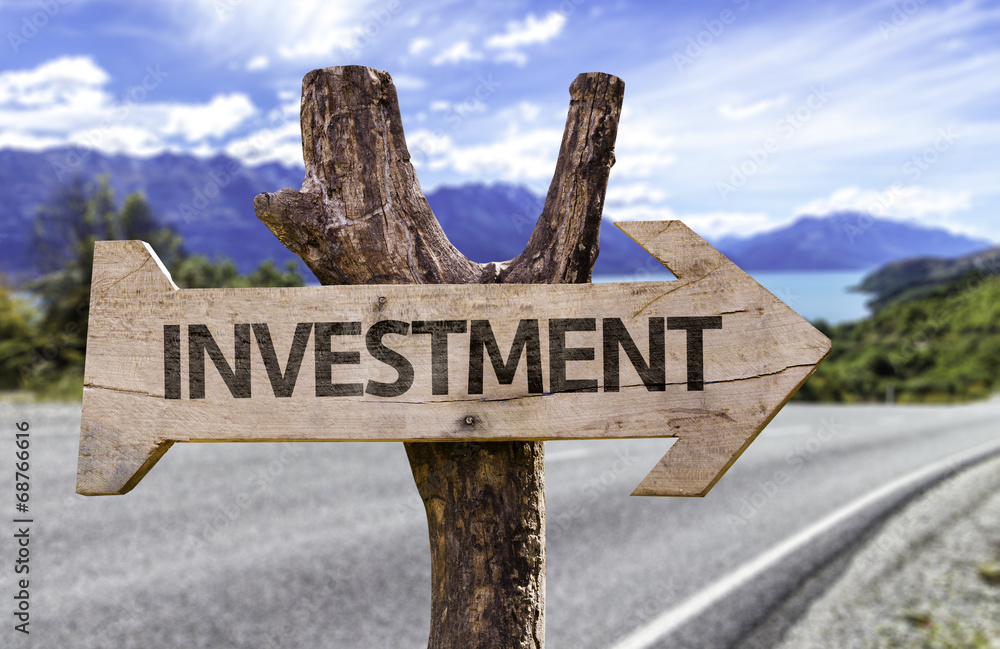 Investment wooden sign with a street on background