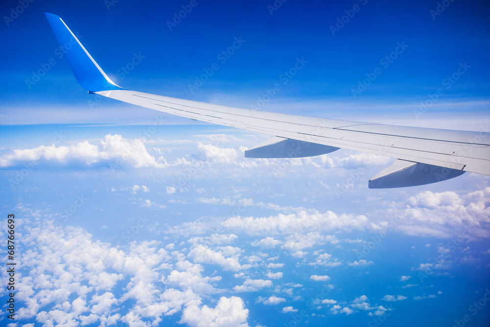 Obraz premium airplane wing with blue sky and white clouds