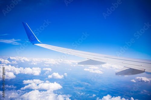 airplane wing with blue sky and white clouds