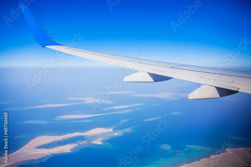 View of jet plane wing with blue sky