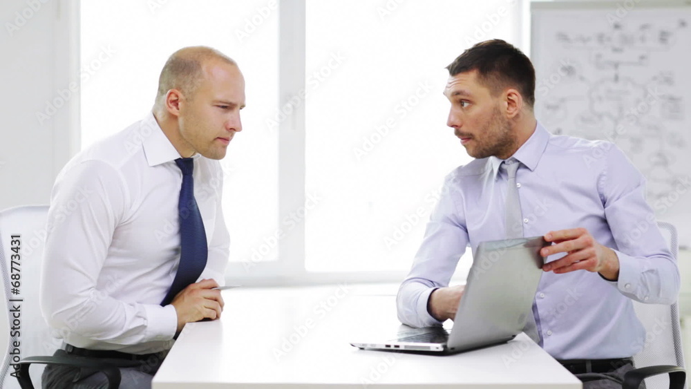two serious businessmen with laptop in office two serious businessmen with laptop in office