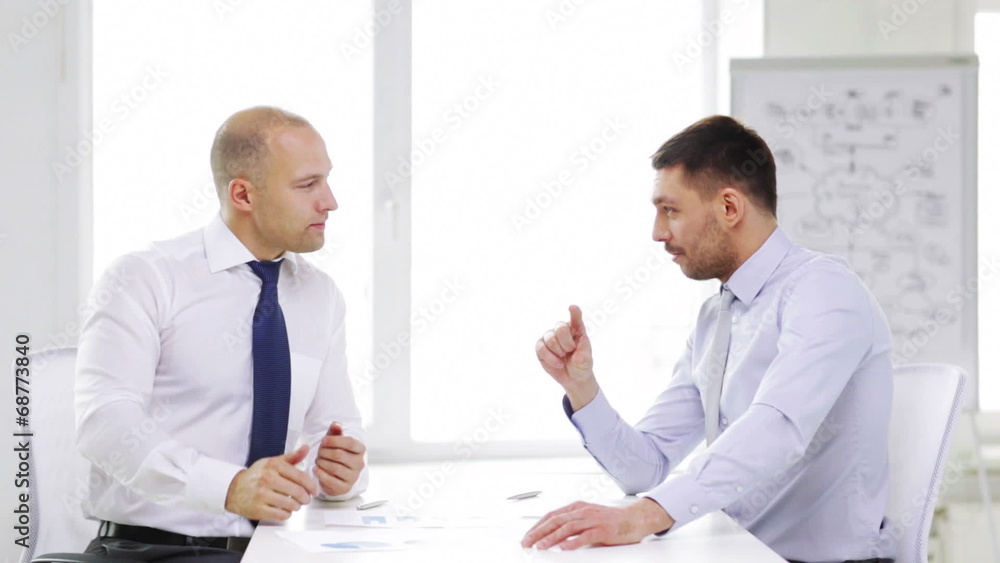 two serious businessmen with charts in office two serious businessmen with charts in office