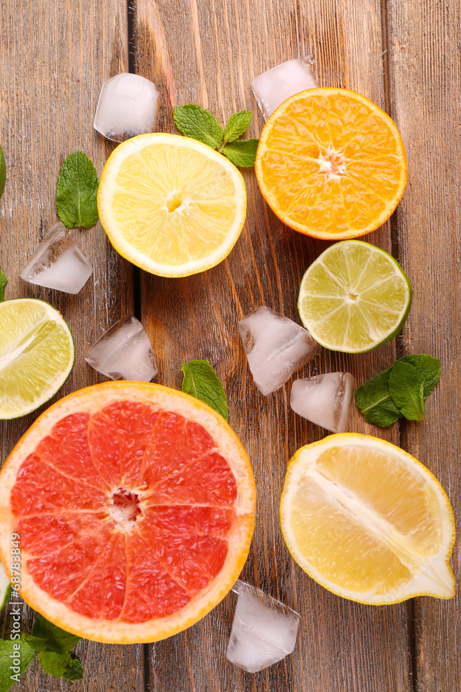 Different sliced juicy citrus fruits with ice on wooden table Different sliced juicy citrus fruits with ice on wooden table