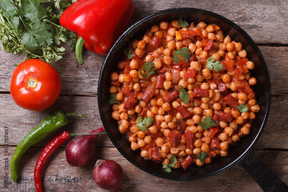 Chickpeas with chorizo in a pan with the ingredients top view Chickpeas with chorizo in a pan with the ingredients top view