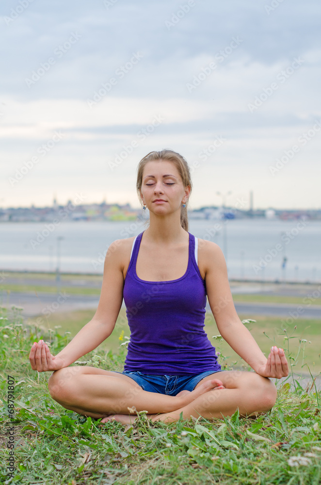 Young pretty woman meditating by the sea.