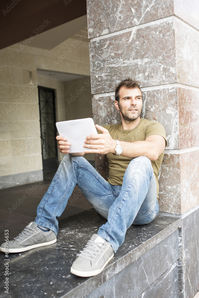 Man sitting in the street with tablet computer.