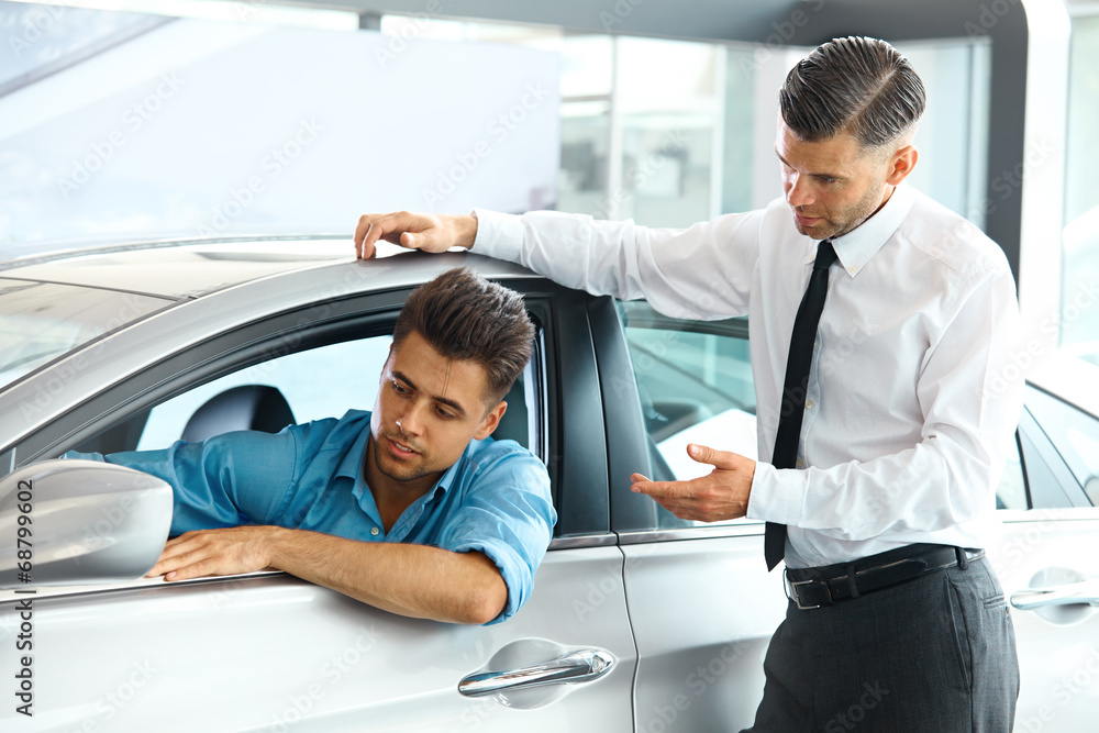 Fototapeta premium Car Sales Consultant Showing a New Car to a Potential Buyer in S