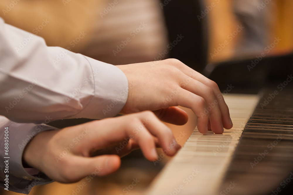 Children's hands on the keyboard of the piano