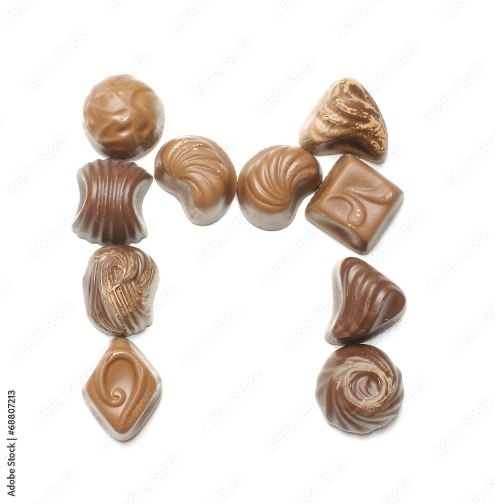 Alphabet letter M arranged from chocolate sweets isolated