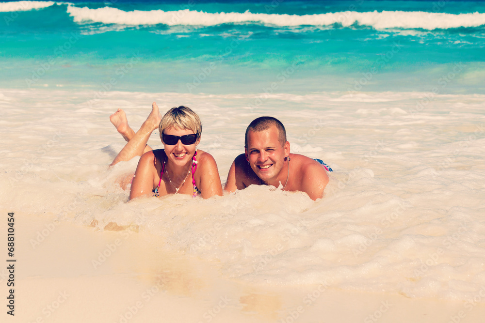 Fototapeta premium Young romantic couple laying on sandy beach
