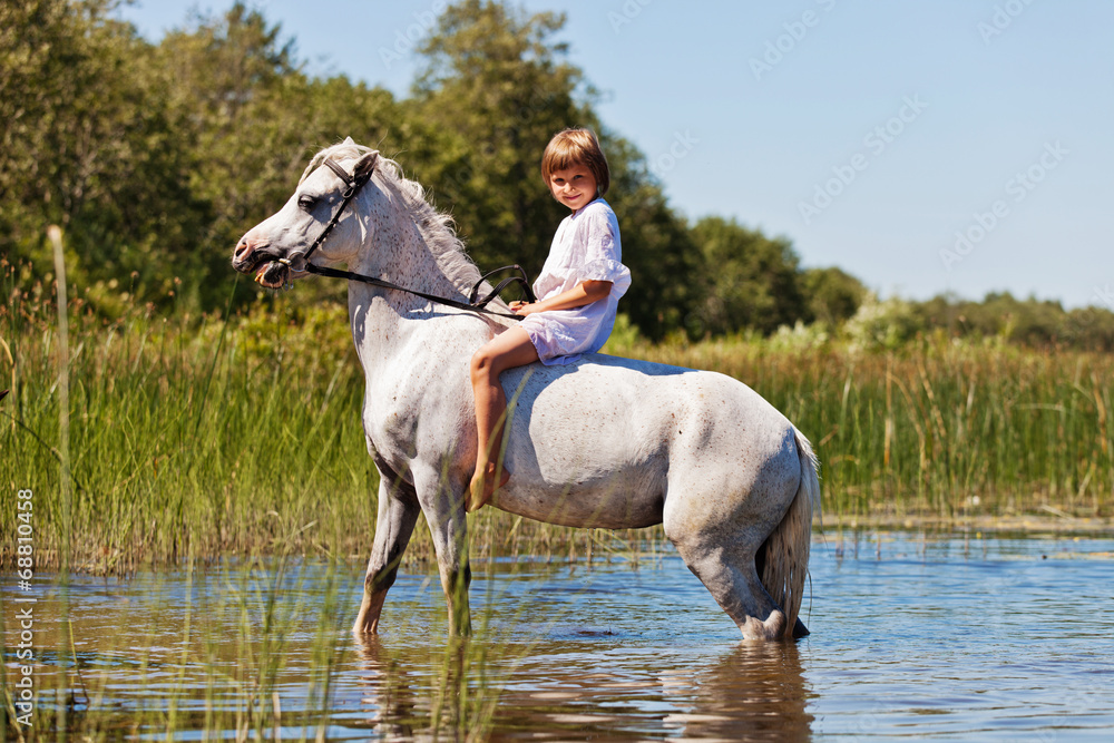 Girl riding a horse in a river