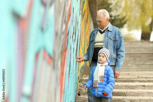Grandfather and grandson paint graffiti on the wall