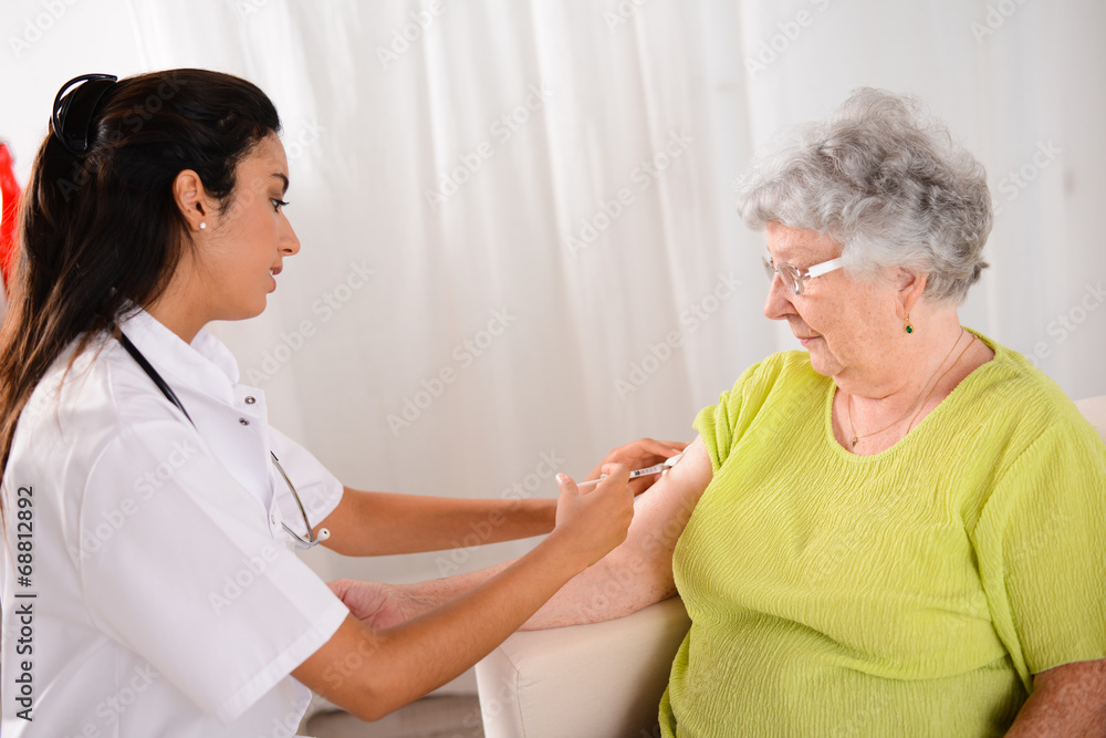 Obraz premium cheerful young nurse giving an injection to elderly woman
