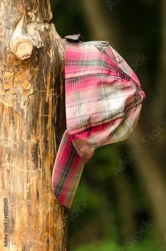 Baseball cap hanging on a wooden post