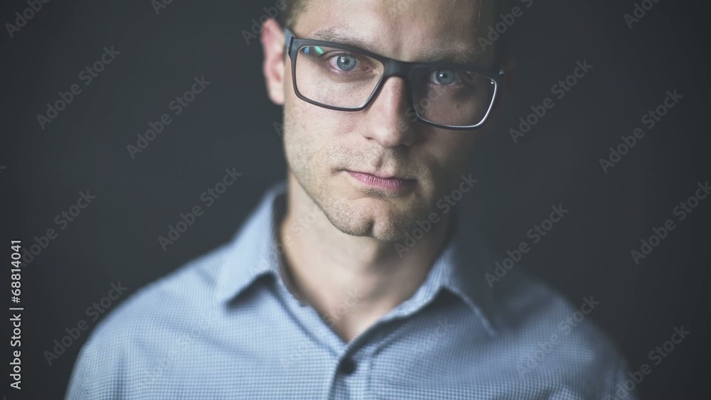 Young man in glasses having a serious look on black background Young man in glasses having a serious look on black background