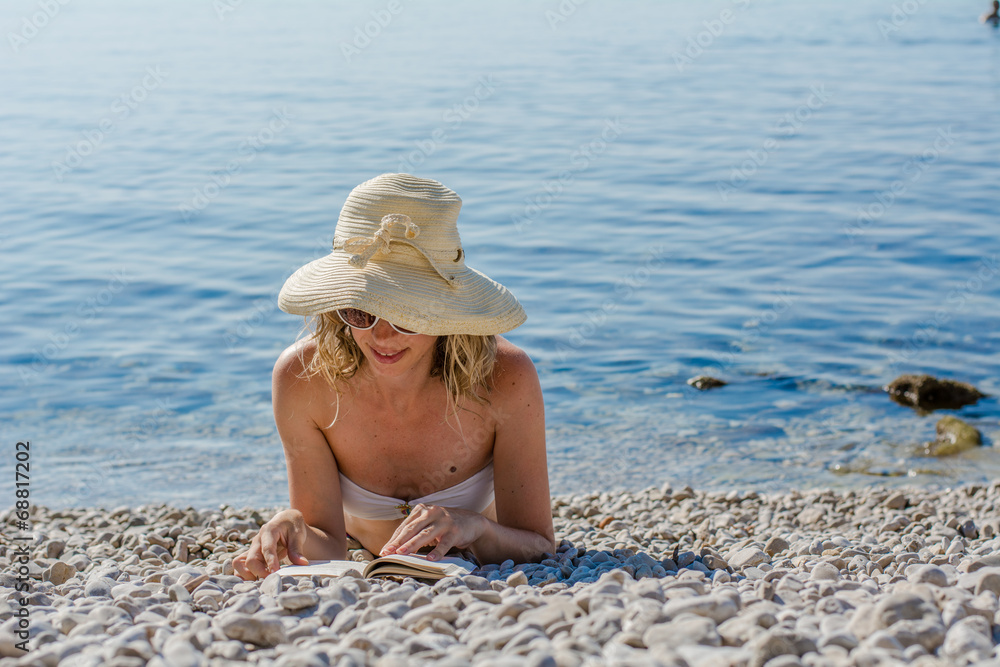 young woman reading book at the beach