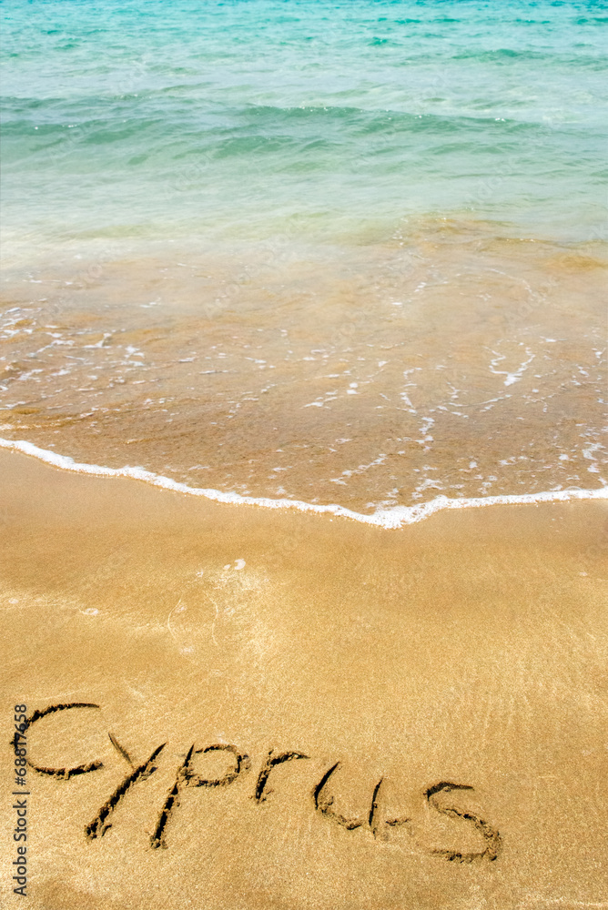 Fototapeta premium Cyprus written in sand on beach with sea in background