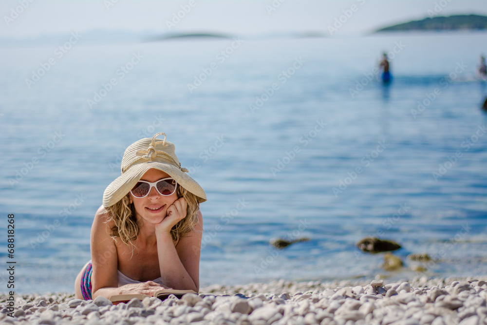 young woman reading book at the beach