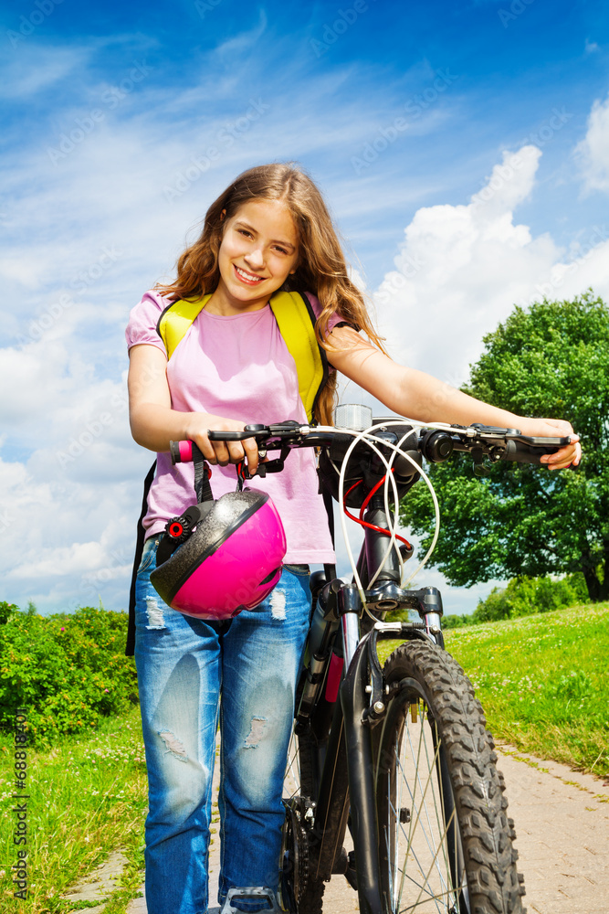 Smiling girl with long hair holds her bike Smiling girl with long hair holds her bike