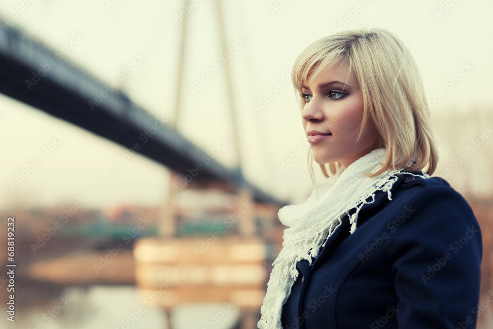 Young blond fashion woman at the river bridge