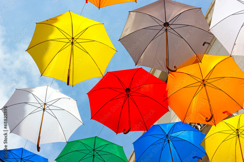 Colorful floating umbrellas against a blue sky