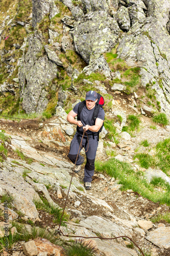 Man hiking on difficult mountain trail with hanging cable