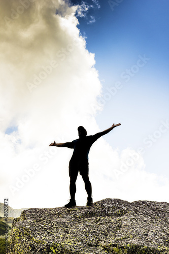 man standing on top of a cliff with arms raised © jinga80