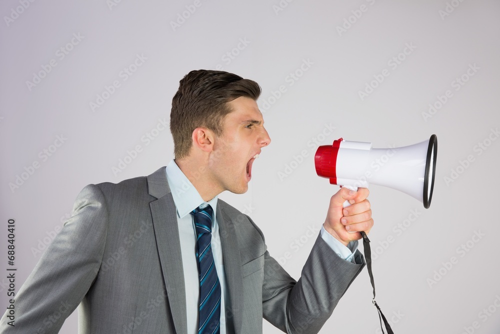 Angry businessman shouting through megaphone Angry businessman shouting through megaphone