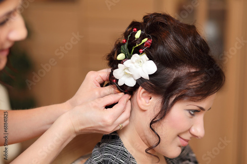 Fryzjerka wpina kwiat we włosy dziewczyny.