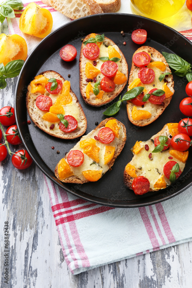 Tasty bruschetta with tomatoes on pan, on old wooden table Tasty bruschetta with tomatoes on pan, on old wooden table